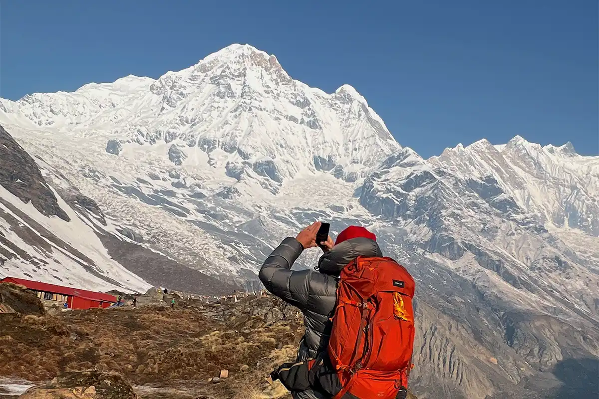 Panoramic view of Annapurna Base Camp surrounded by snow-capped Himalayan peaks under a clear blue sky.